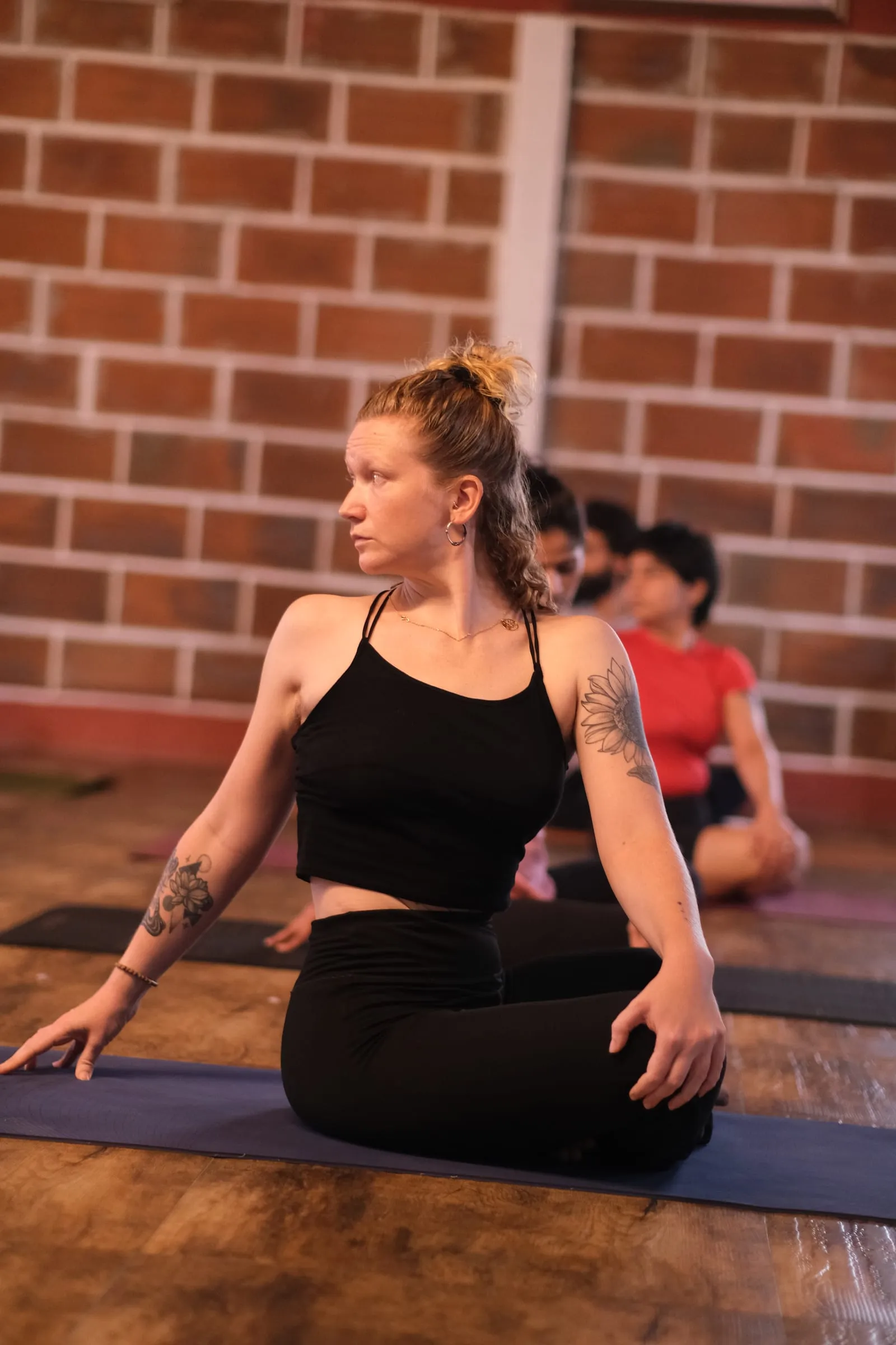 Laura in a seated twist on her mat in a practice room